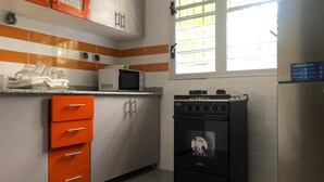 Eine Küche mit Mikrowelle, Herd und orangenen Schränken.