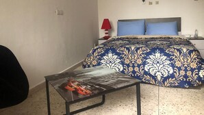 Ein Schlafzimmer mit einem Bett, einem Nachttisch, einer roten Lampe und einem kleinen Tisch mit einer Zeitschrift.