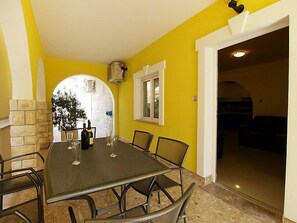 A dining area with a table and chairs, a stone wall, and a window. - Apartment Anić by Interhome (Novigrad (Zadar))