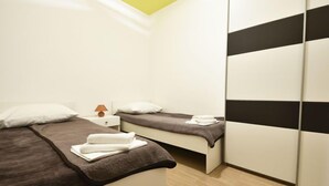 A modern bedroom with two beds, a nightstand, a lamp, and a wardrobe. - Apartment Anić by Interhome (Novigrad (Zadar))