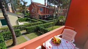 Un balcon avec une table dressée pour deux personnes, agrémenté d’un panier de fruits et d’une nappe.