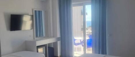Ein Hotelzimmer mit zwei Betten, einem Fernseher, einer Klimaanlage, einem Schreibtisch und Blick ins Freie.
