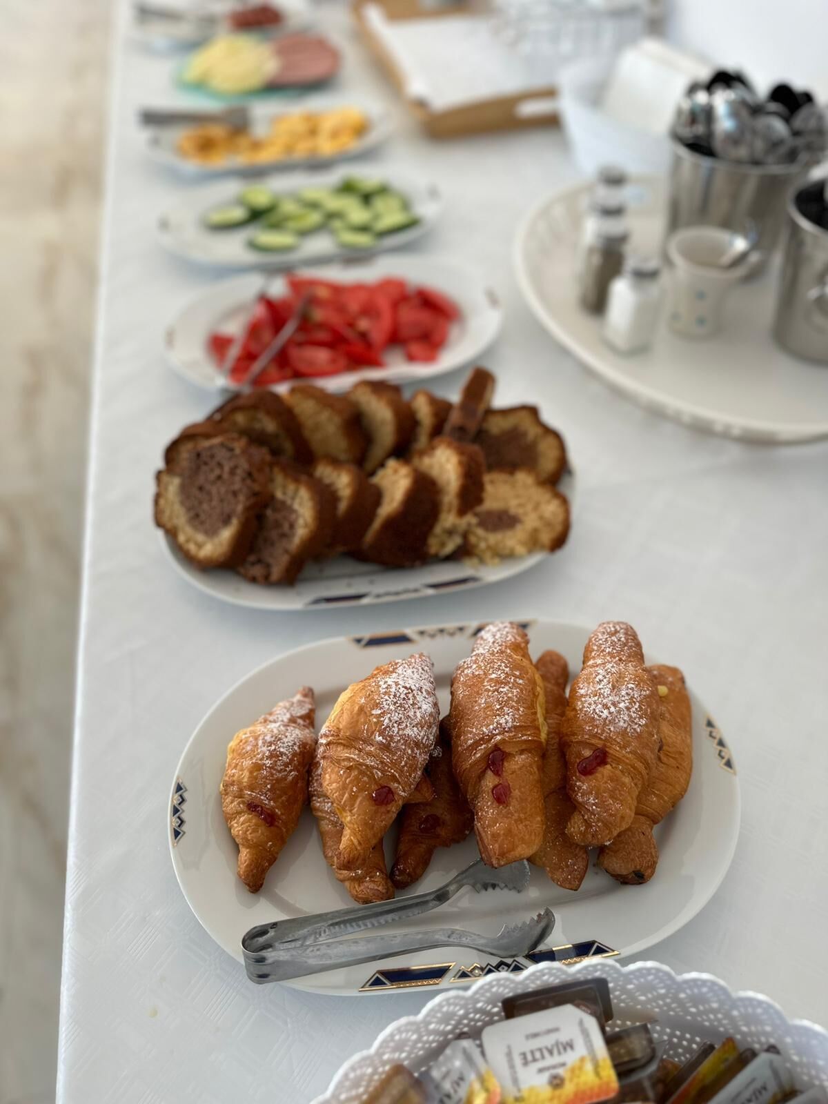 Ein Tisch mit verschiedenen Speisen, darunter Brot, Croissants und Obst.