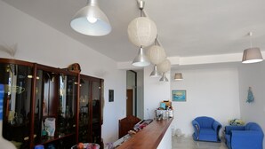 A modern living room with a wooden coffee table, blue armchairs, and a wooden cabinet with glass doors.