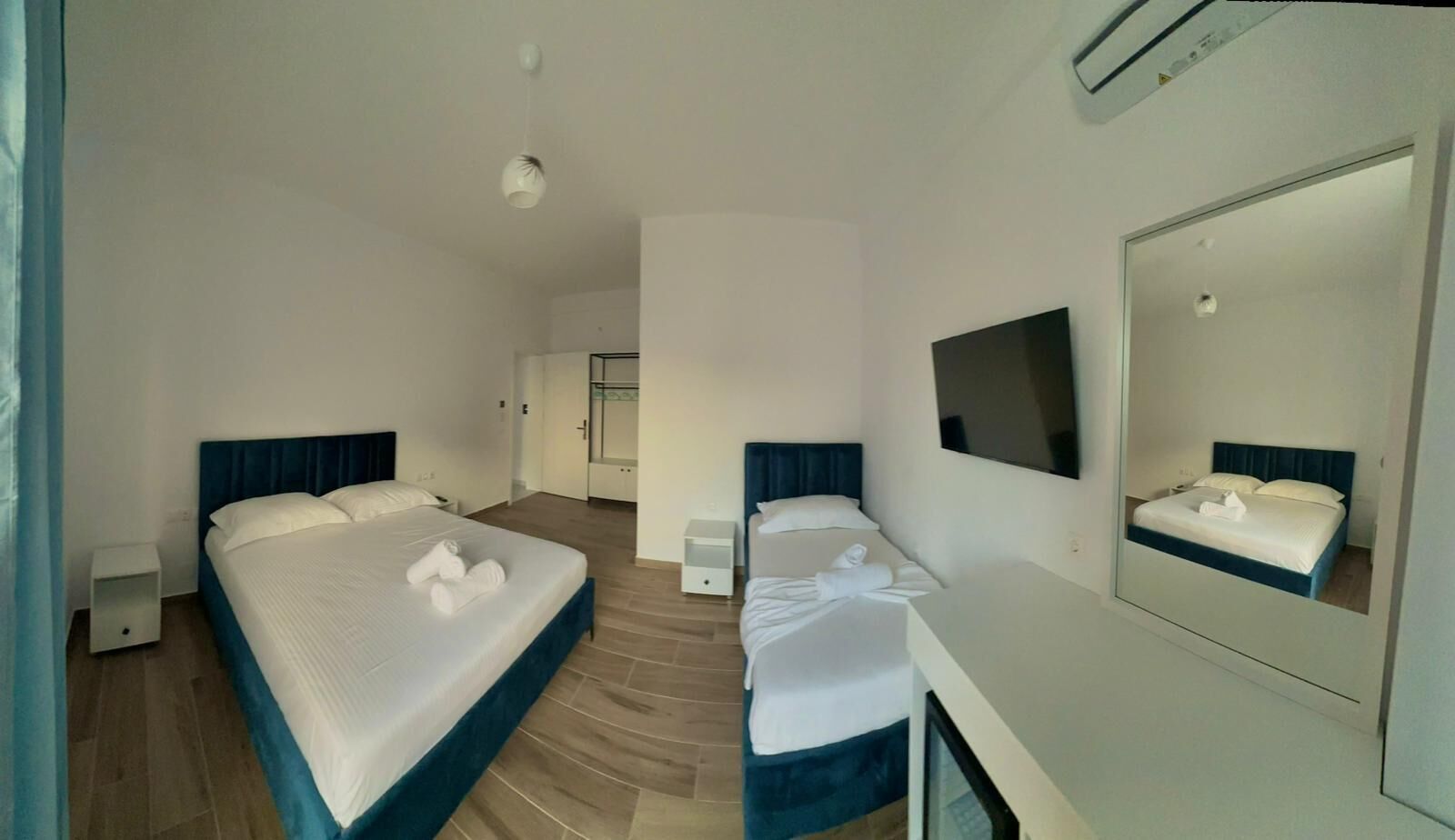 A hotel room with two beds, a large mirror, and a small bedside table.