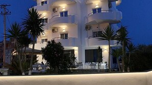 A multi-story hotel with balconies, outdoor seating, and palm trees.
