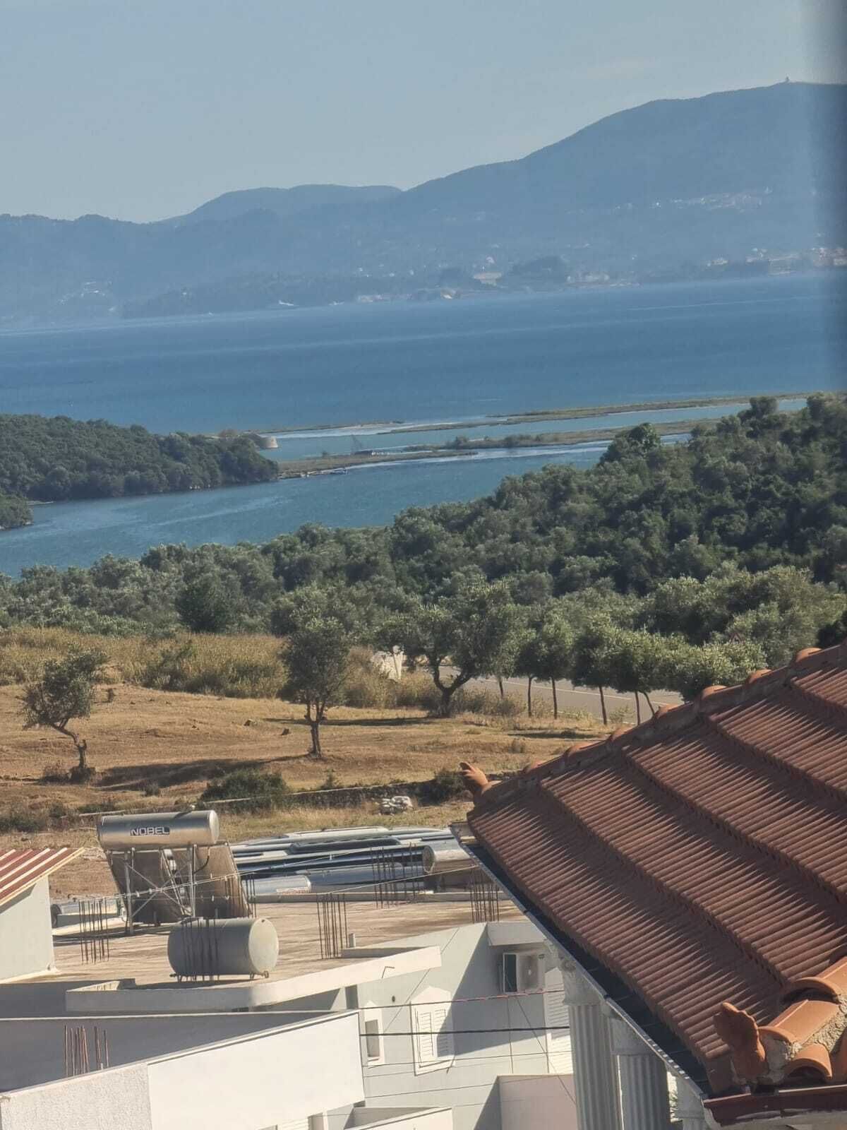 Une vue sur la côte, avec un ciel dégagé, une étendue d’eau et un paysage vallonné à l’horizon.
