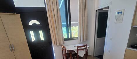 A hotel room with a bed, a table with chairs, a wardrobe, a door, and a window with curtains.