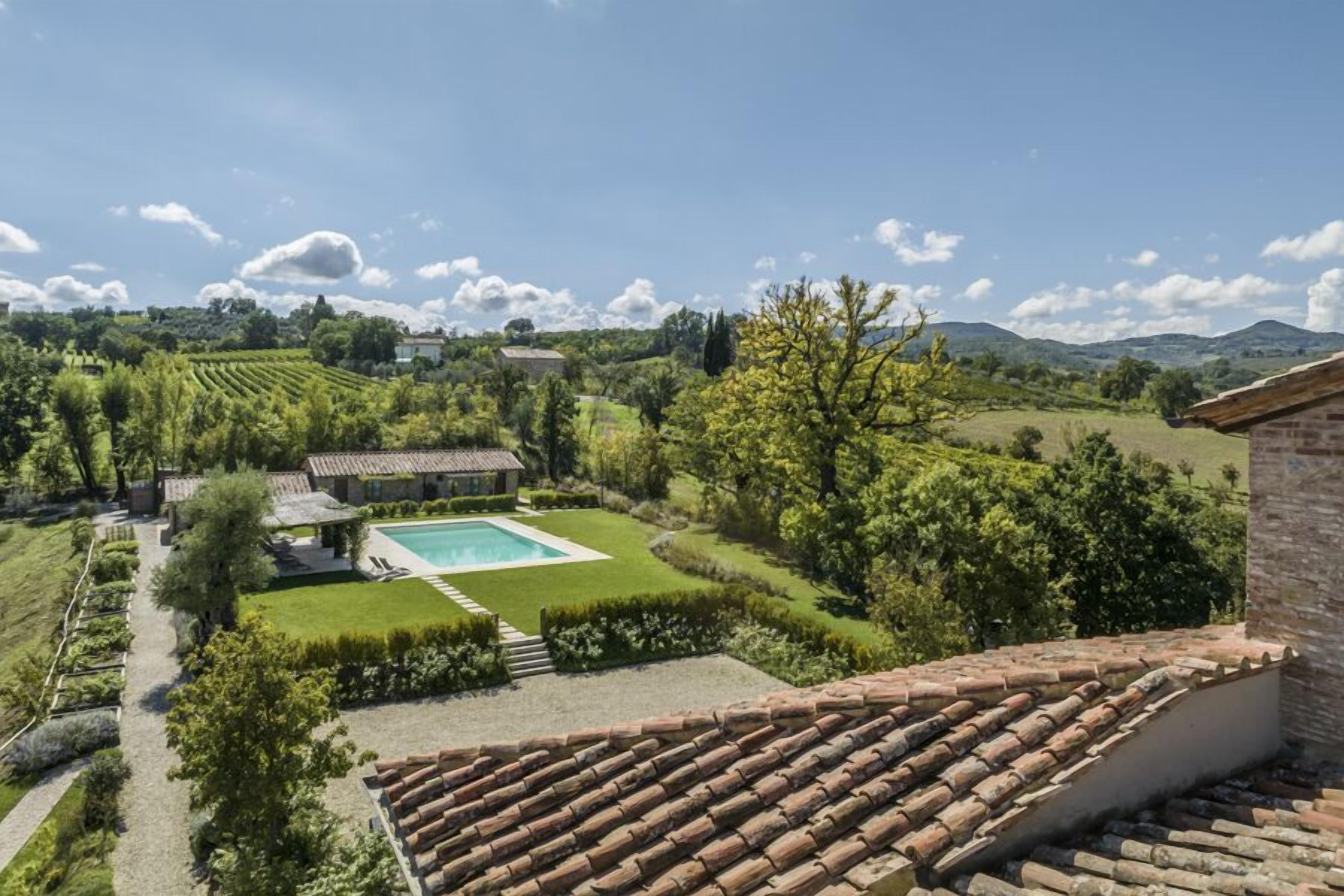 Eine Villa mit Swimmingpool, Terrakottadach und üppigem Garten.