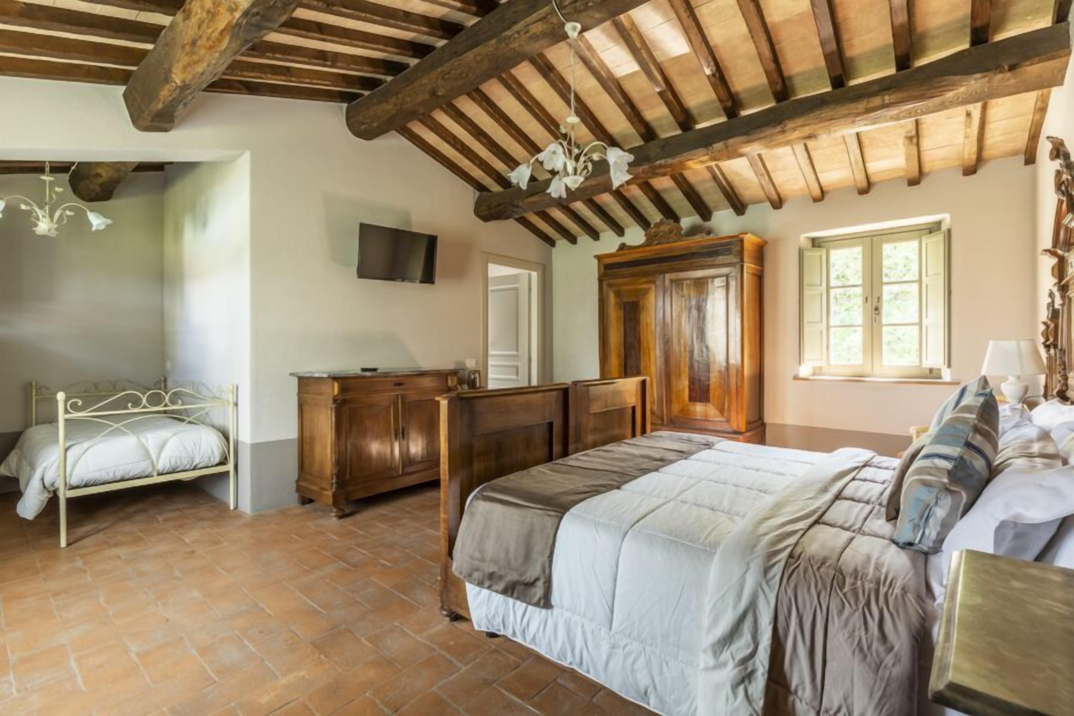 Ein Schlafzimmer mit einem großen Bett, einem Holzschrank und einem Steinfliesenboden.