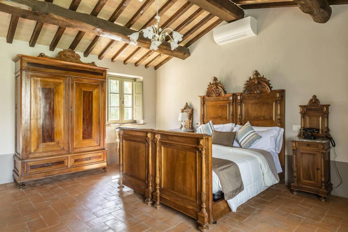 A bedroom with a wooden bed, a large wardrobe, and a classic chandelier.