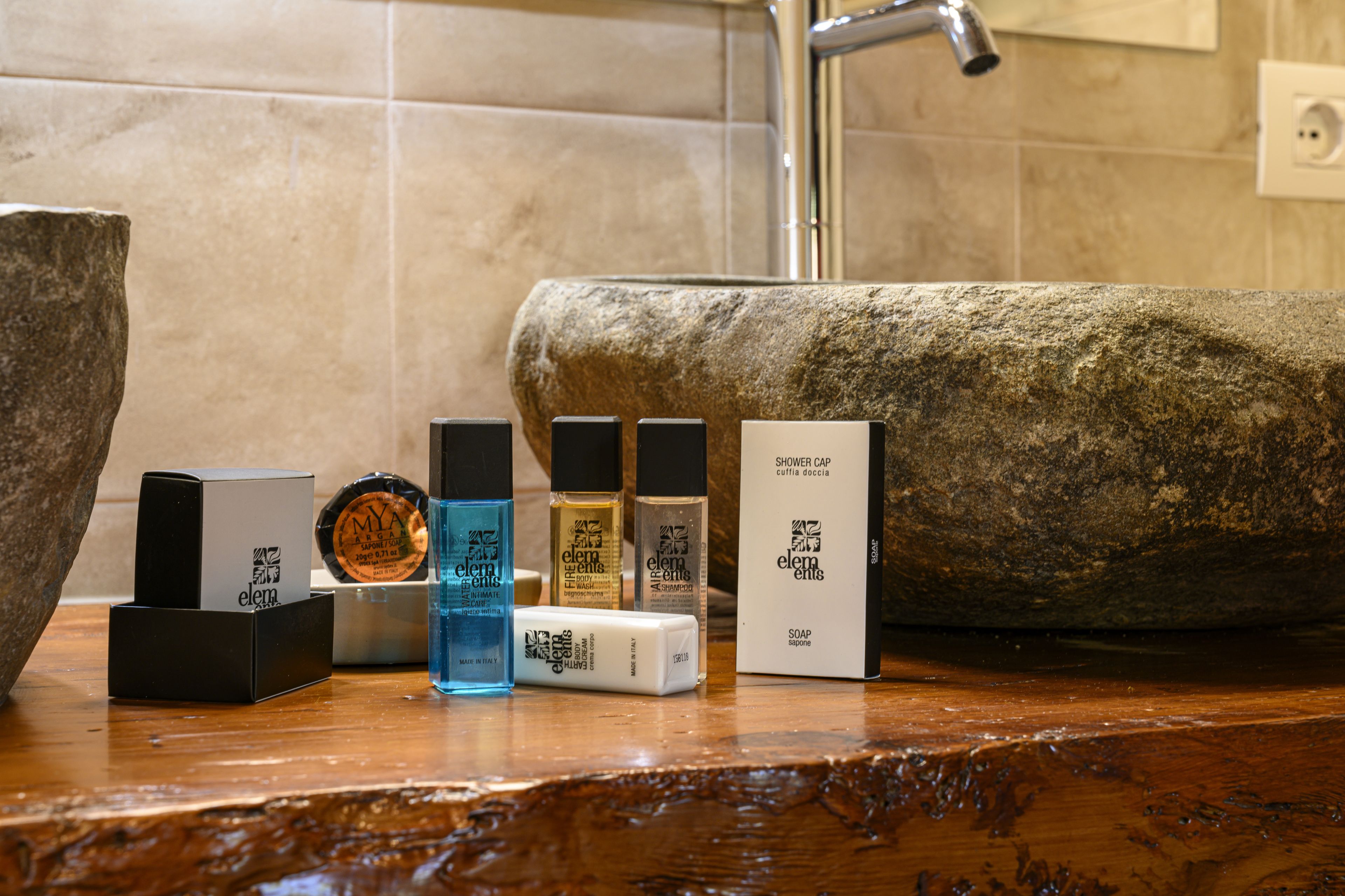 Un meuble-lavabo de salle de bain avec divers produits de toilette et un grand vasque en pierre.