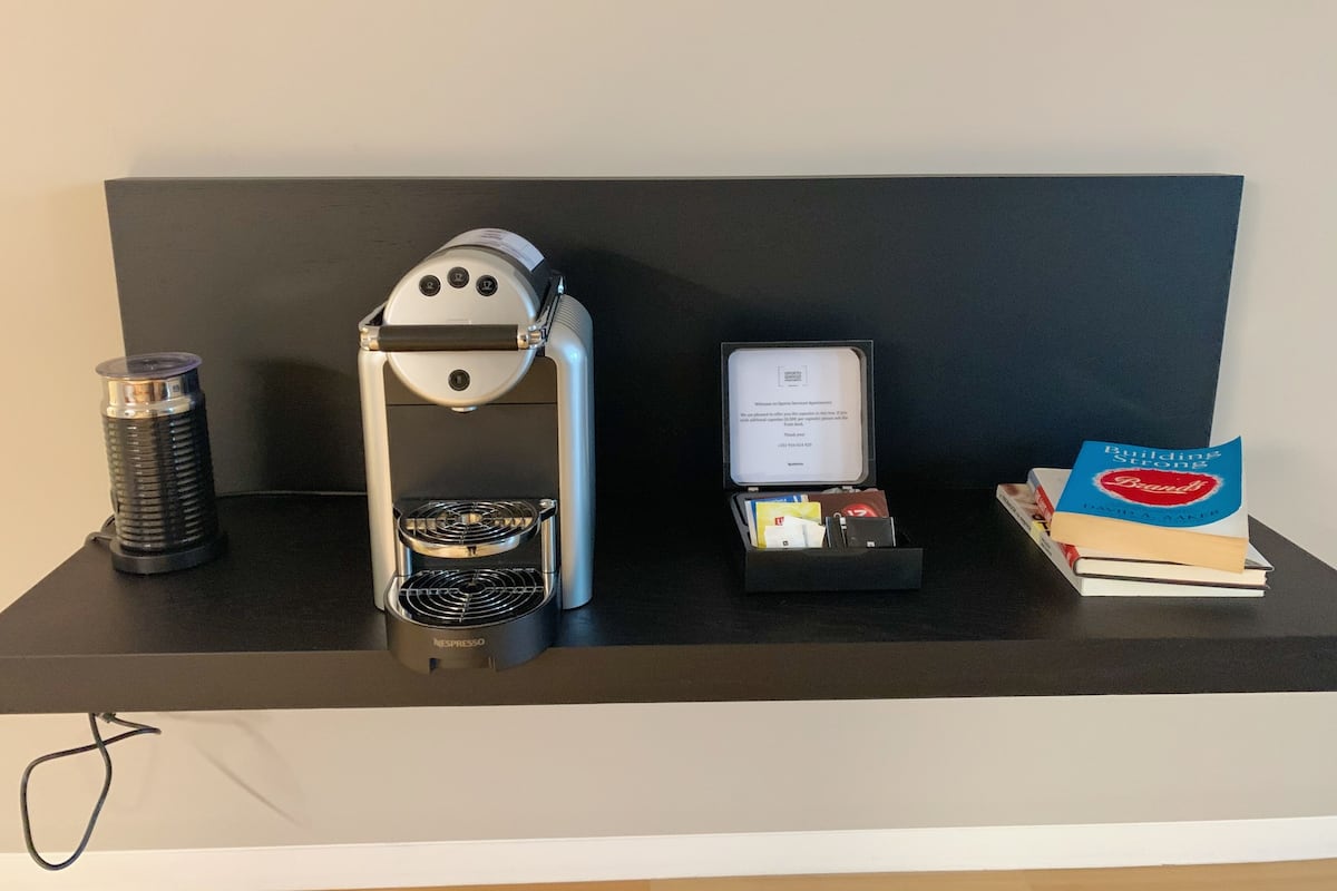 Una cafetera, un libro titulado 'Building Strong Brands' de David Aaker, y una caja pequeña con una tarjeta sobre una encimera negra.