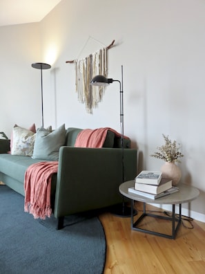 Un salon moderne avec un canapé vert, une table basse ronde et un lampadaire.