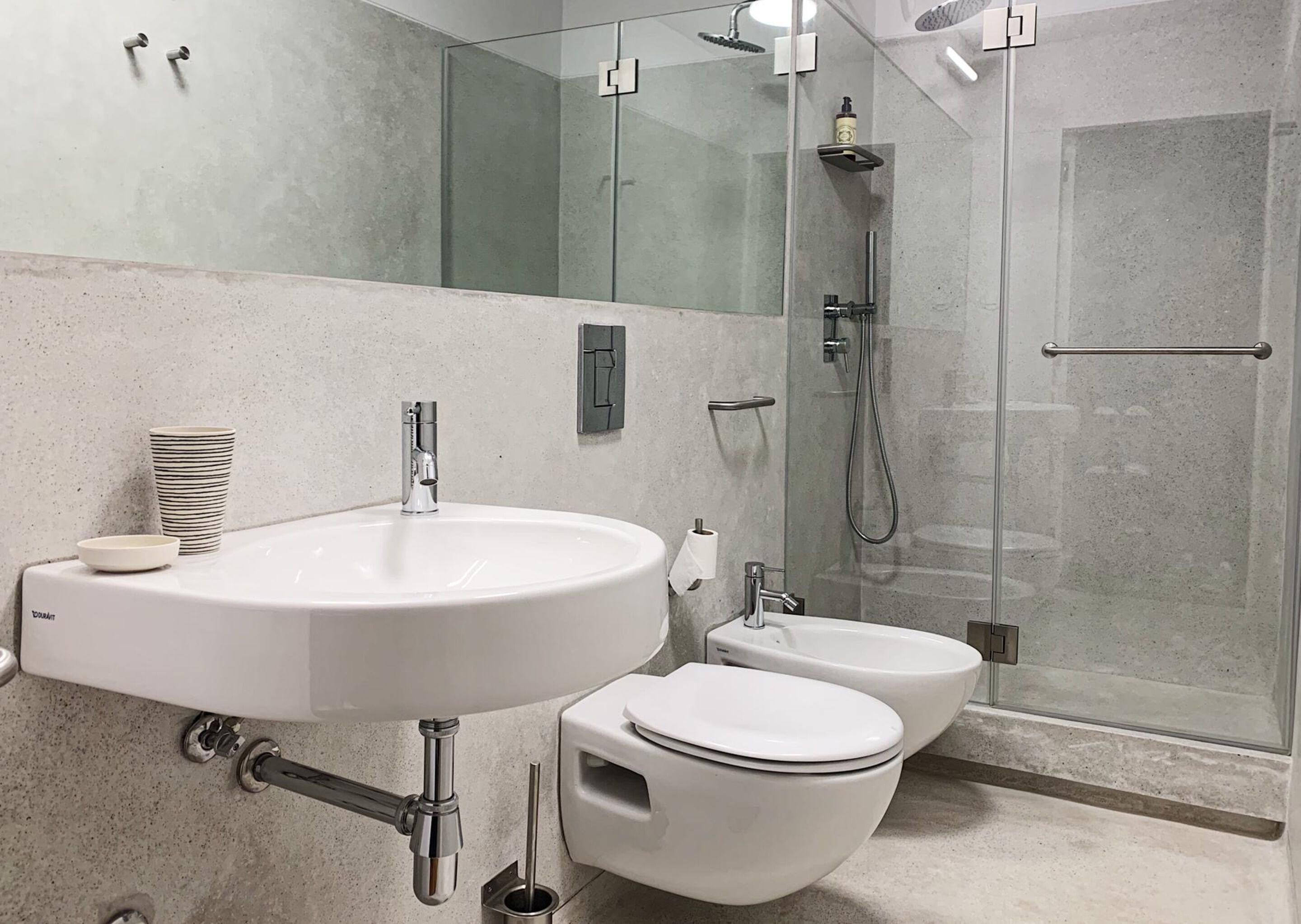 A modern bathroom with a large sink, toilet, and glass-enclosed shower.