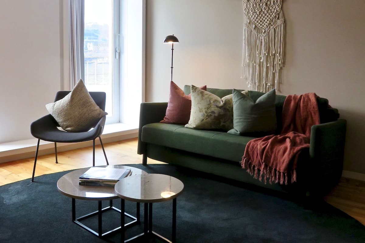 Una sala de estar moderna con un sofá verde, una mesa de centro redonda y una silla negra.
