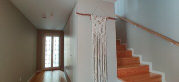 Uma escada com degraus de madeira e uma tapeçaria de macramé na parede.