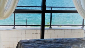 A bedroom with a bed, a view of the sea, and curtains. - Flat Bellmare (Florianópolis)