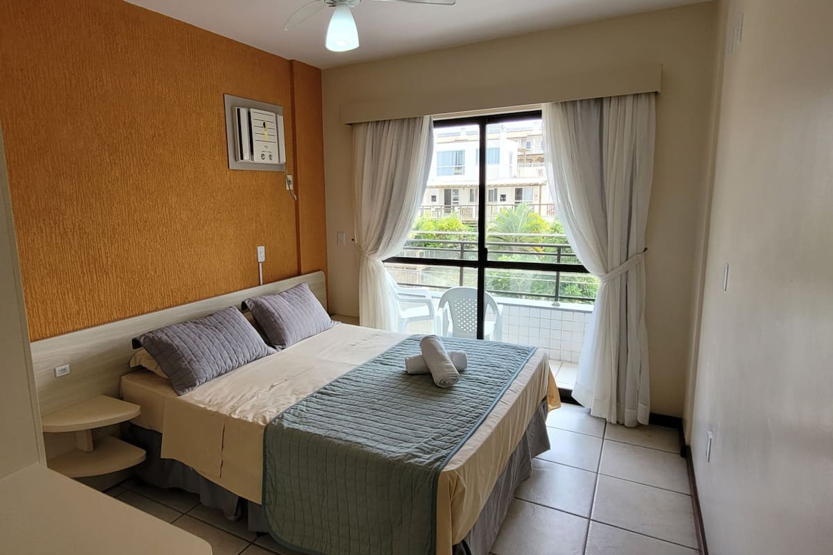 Une chambre à coucher avec un lit, une table de chevet et une fenêtre avec des rideaux.