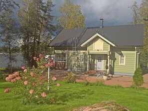 Une maison à deux étages, avec un toit sombre, un porche à l’avant et une petite terrasse.