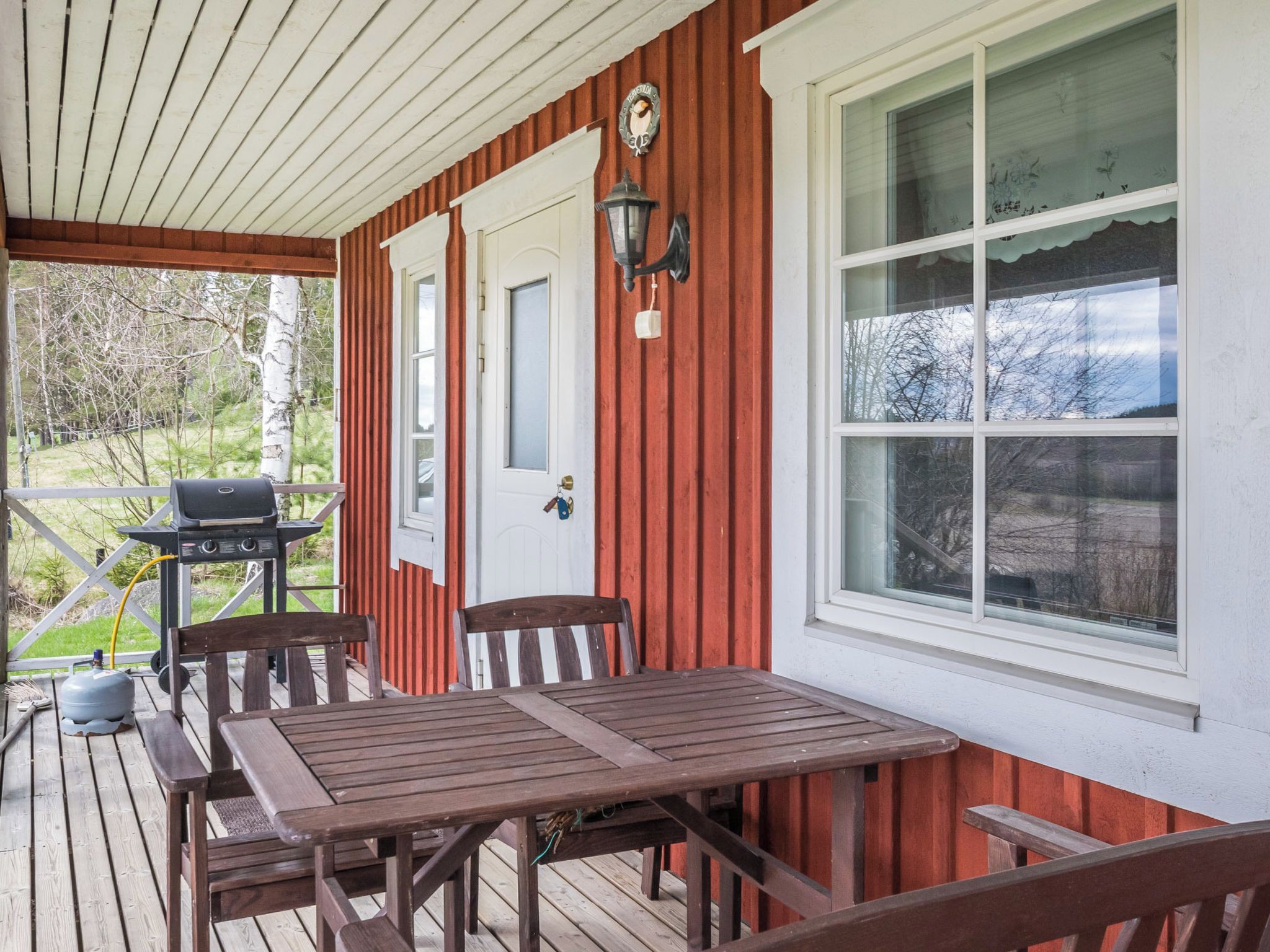 Une terrasse en bois avec un barbecue, une table et des chaises.