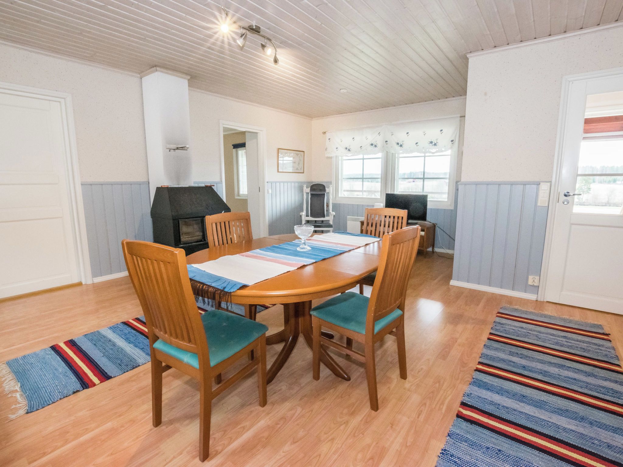 Un espace repas comprenant une table en bois, des chaises et un barbecue encastré.