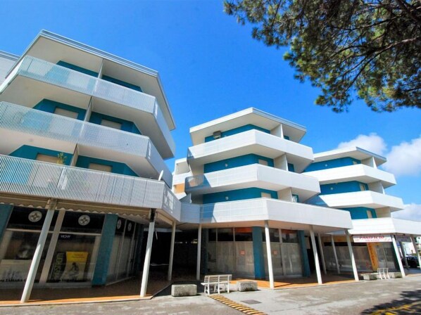 A modern multi-story building with balconies and a covered entrance area.