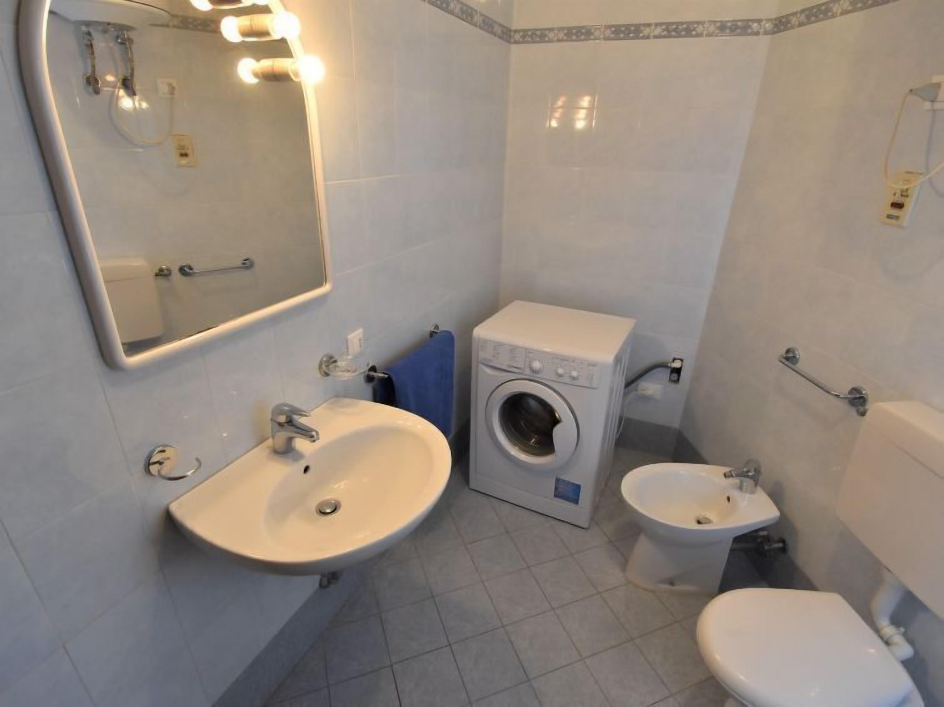 Ein Badezimmer mit Waschbecken, Waschmaschine, Bidet und Toilette.