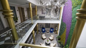Een meerlaags interieur met een geruit vloerkleed, een glazen balustrade en een kroonluchter.