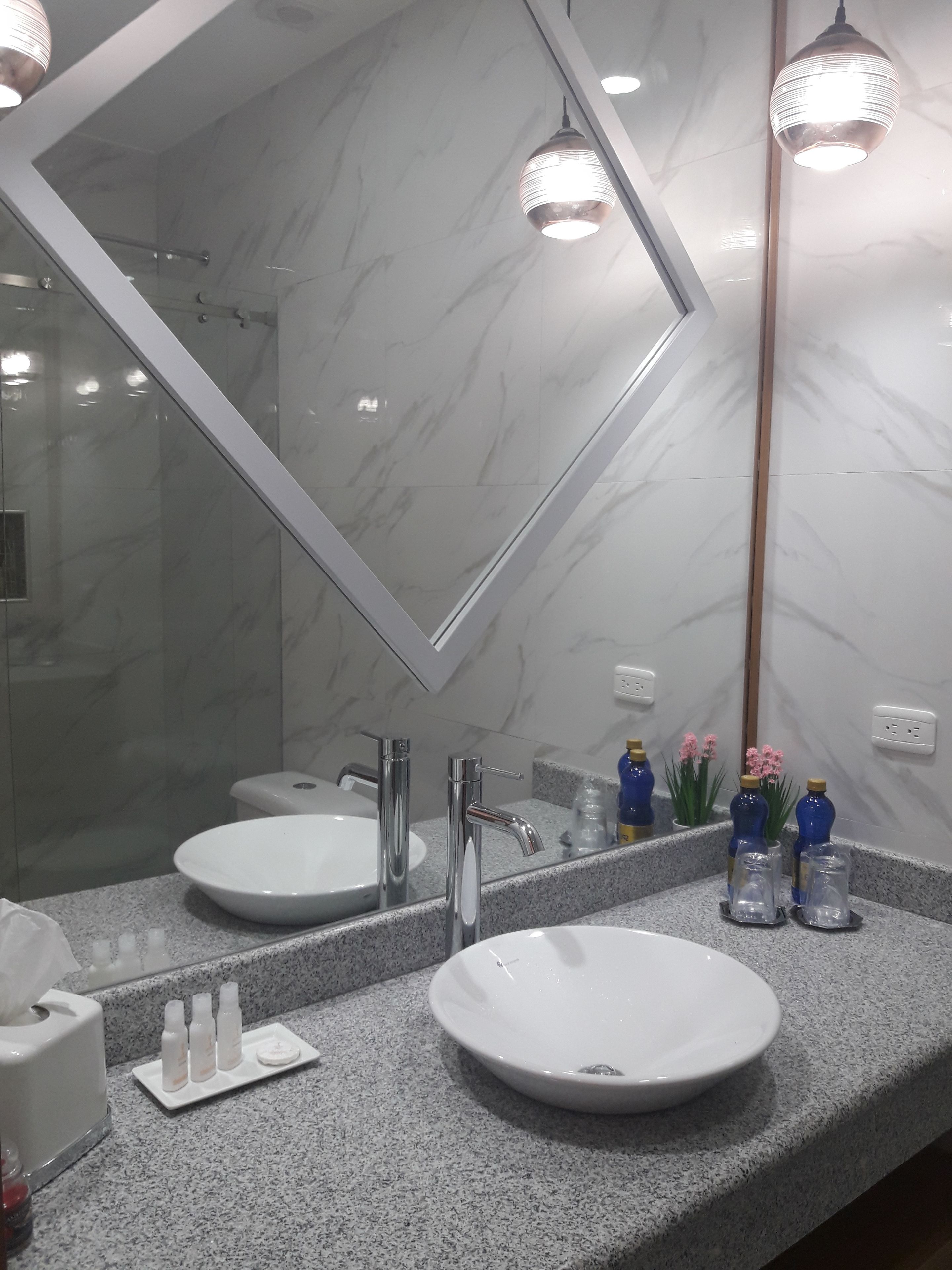 Un baño con un espejo grande, dos lavamanos y una encimera de granito.
