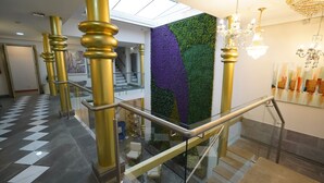 Een modern interieur met een glazen trap, gouden accenten en een groene en paarse wand.