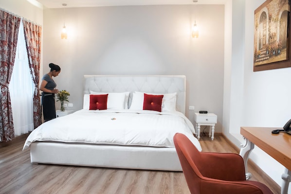 A bedroom with a large bed, a nightstand, a desk, and a chair. - Adamas House Hotel (Quito)