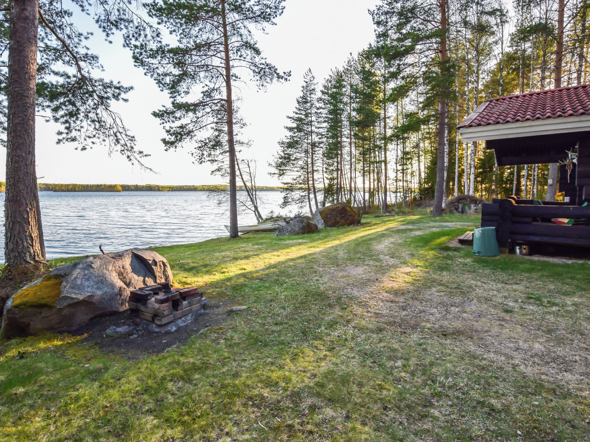A lakeside cabin with a fire pit, a covered outdoor seating area, and a view of the lake.