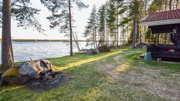 A lakeside cabin with a fire pit, a covered outdoor seating area, and a view of the lake.