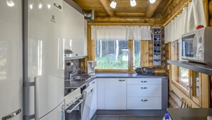 A compact kitchen with white cabinets, a built-in oven, a microwave, and a coffee maker. - Leporanta by Interhome (Kerimäki)