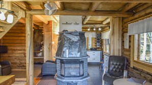 A log cabin interior with a stone fireplace, wooden furniture, and a view of the outdoors. - Leporanta by Interhome (Kerimäki)