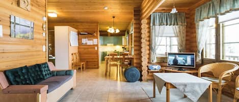 Un acogedor interior de cabaña con sofá, mesa de comedor y televisor.