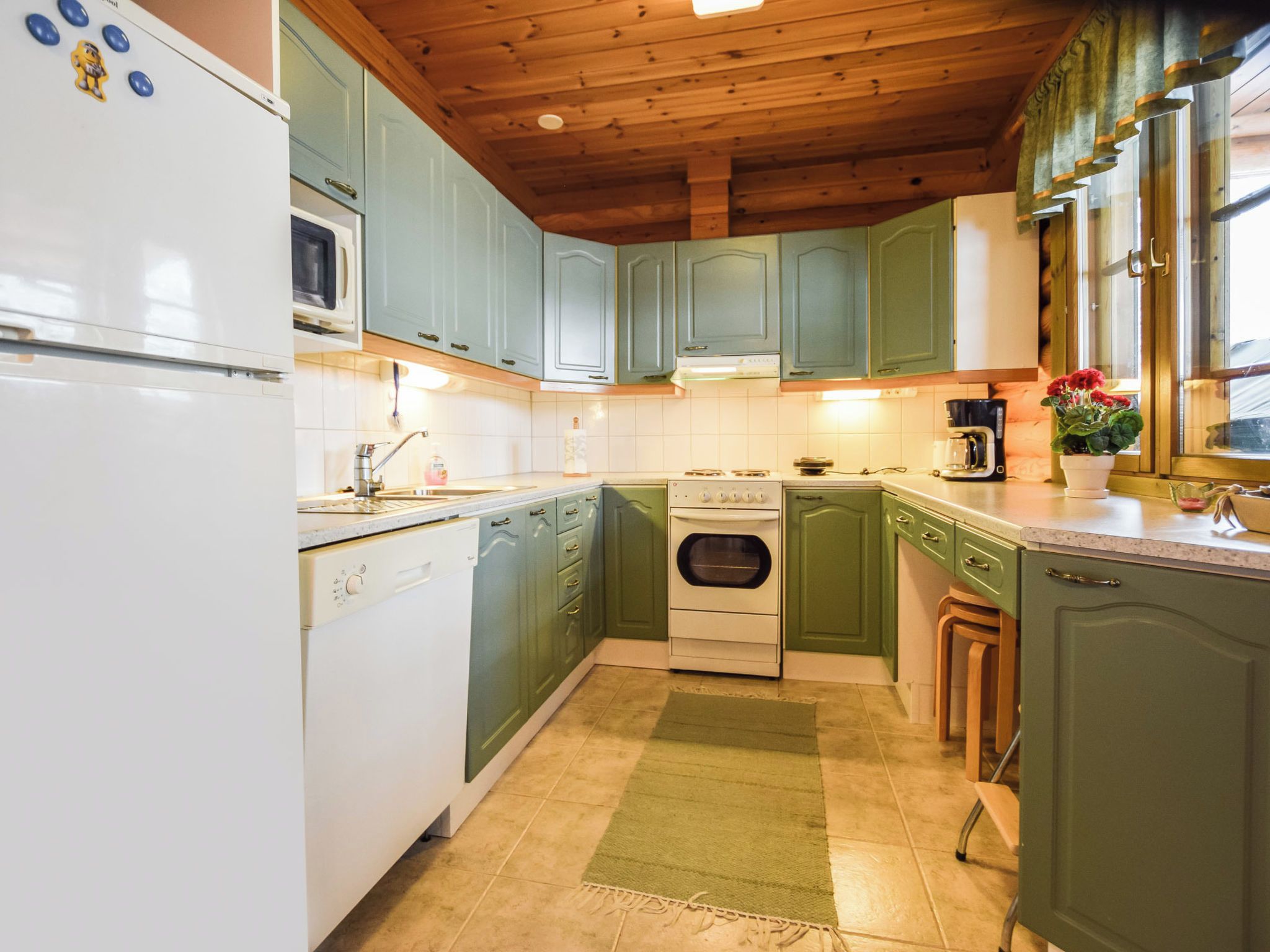 A kitchen with green cabinets, a white dishwasher, and a stove.