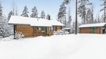 Een chalet met een sneeuwbedekte dak, omringd door hoge dennenbomen.
