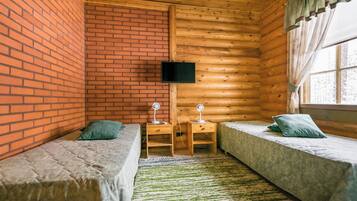 Een kamer met twee bedden, een aan de muur bevestigde televisie en een raam met gordijnen.