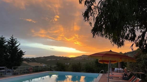 A swimming pool with a sunset view, lounge chairs, and an umbrella. - Contrada Brecciano by Interhome (Città Sant'Angelo)