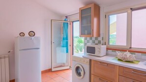 A compact kitchen with a washing machine, a microwave, and a refrigerator. - Contrada Brecciano by Interhome (Città Sant'Angelo)