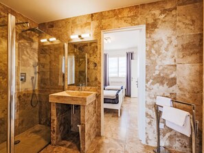 Een moderne badkamer met een douchecabine van glas, een marmeren wastafel en een inloopdouche.