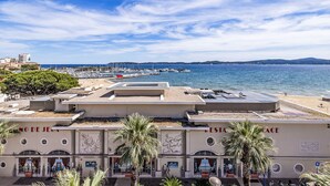 Un hotel frente al mar con terraza en la azotea, vistas a la playa y zona de comedor.
