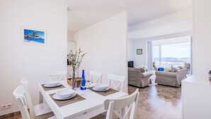 Una sala de estar moderna con comedor, un conjunto de sofás y vistas a la ciudad.