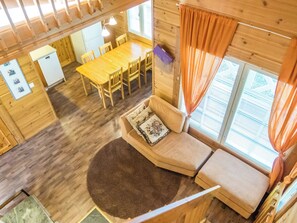 A cabin interior with a dining area, a sofa with a rug, and a window with curtains. - Klz 1. akaatti by Interhome (Sotkamo)