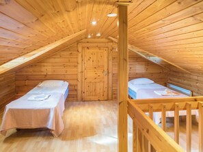 A wooden attic bedroom with two beds, a wooden door, and a wooden railing. - Klz 1. akaatti by Interhome (Sotkamo)