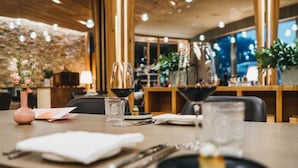 Une table à manger dressée avec un verre à vin, une assiette à dessert et un vase rempli de fleurs.