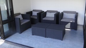 Un patio couvert aménagé avec un coin salon comprenant deux canapés et une table basse.