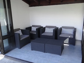 A covered patio area with a seating arrangement consisting of two sofas and a coffee table. - Barbara Ost Appartement/Fewo 2-Bettwohnung by Interhome (Engelberg)